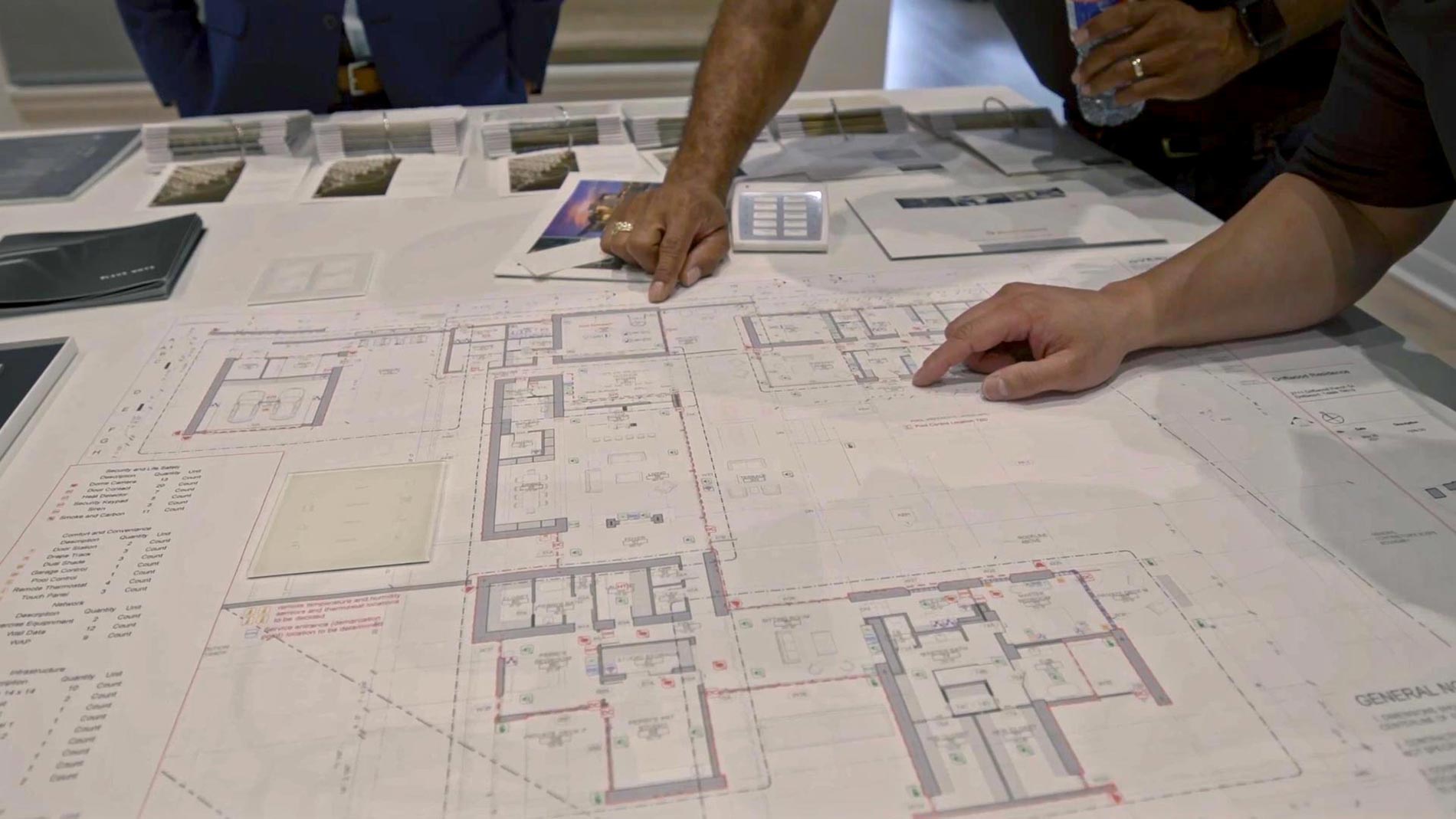 Two people reviewing a detailed floor plan on a large table