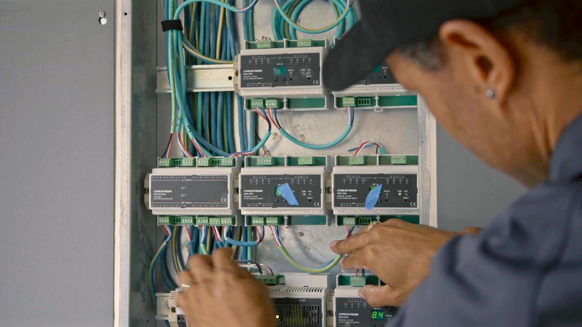Hands of a technician wiring an electrical control panel with blue cables